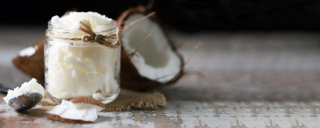 crème de noix de coco dans un pot en verre transparent avec morceaux de noix de coco en arrière-plan